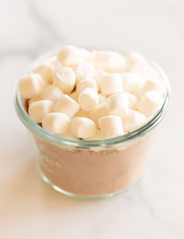 A small glass jar full of homemade hot chocolate mix topped with small marshmallows.