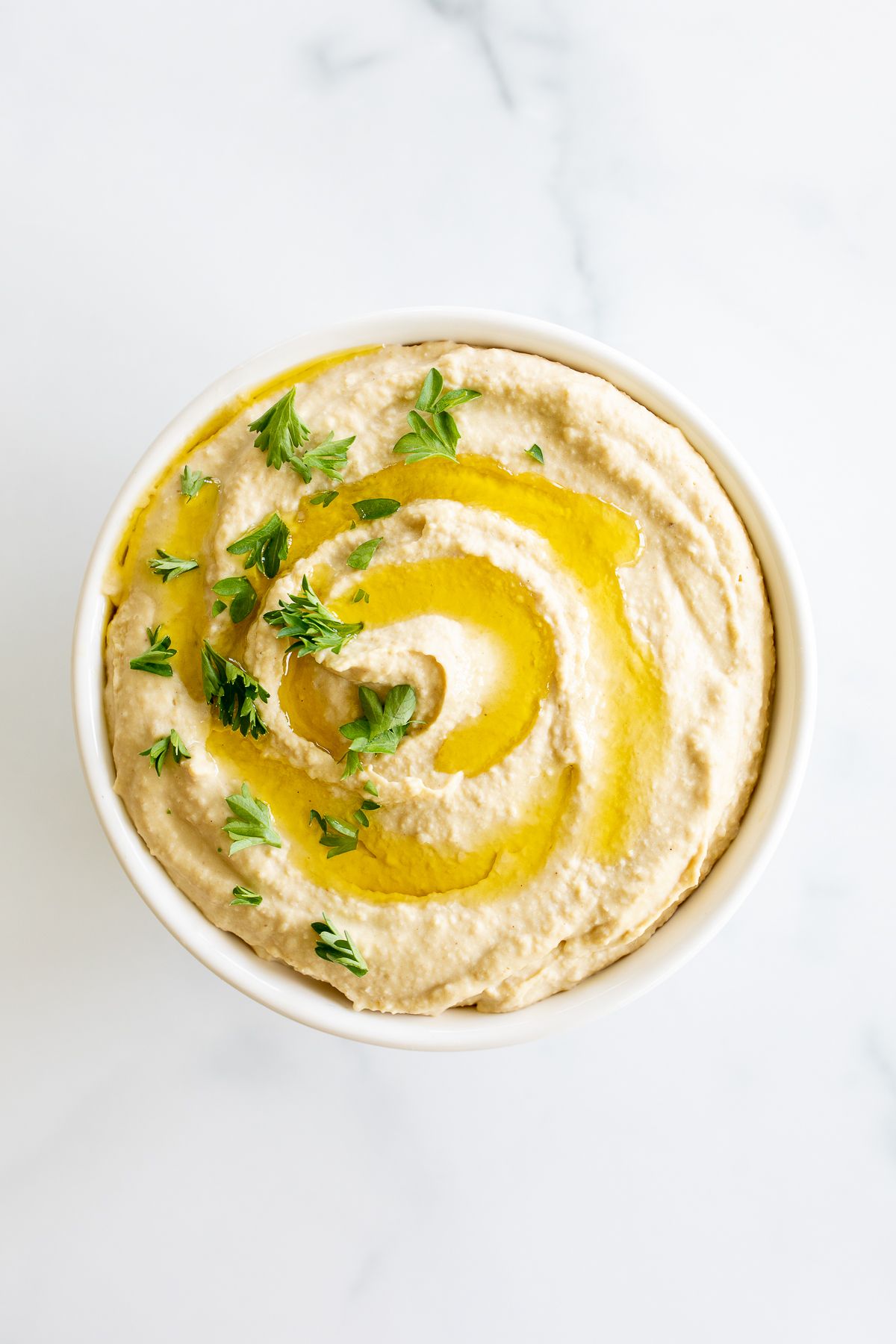 A small bowl of an easy hummus recipe on a white countertop.