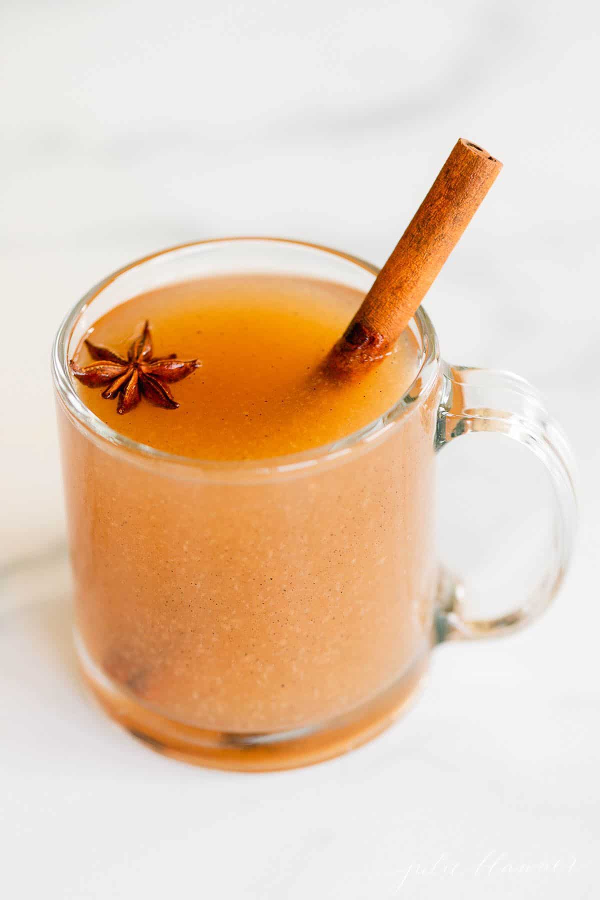 A single glass mug full of homemade pear cider, cinnamon stick for garnish.