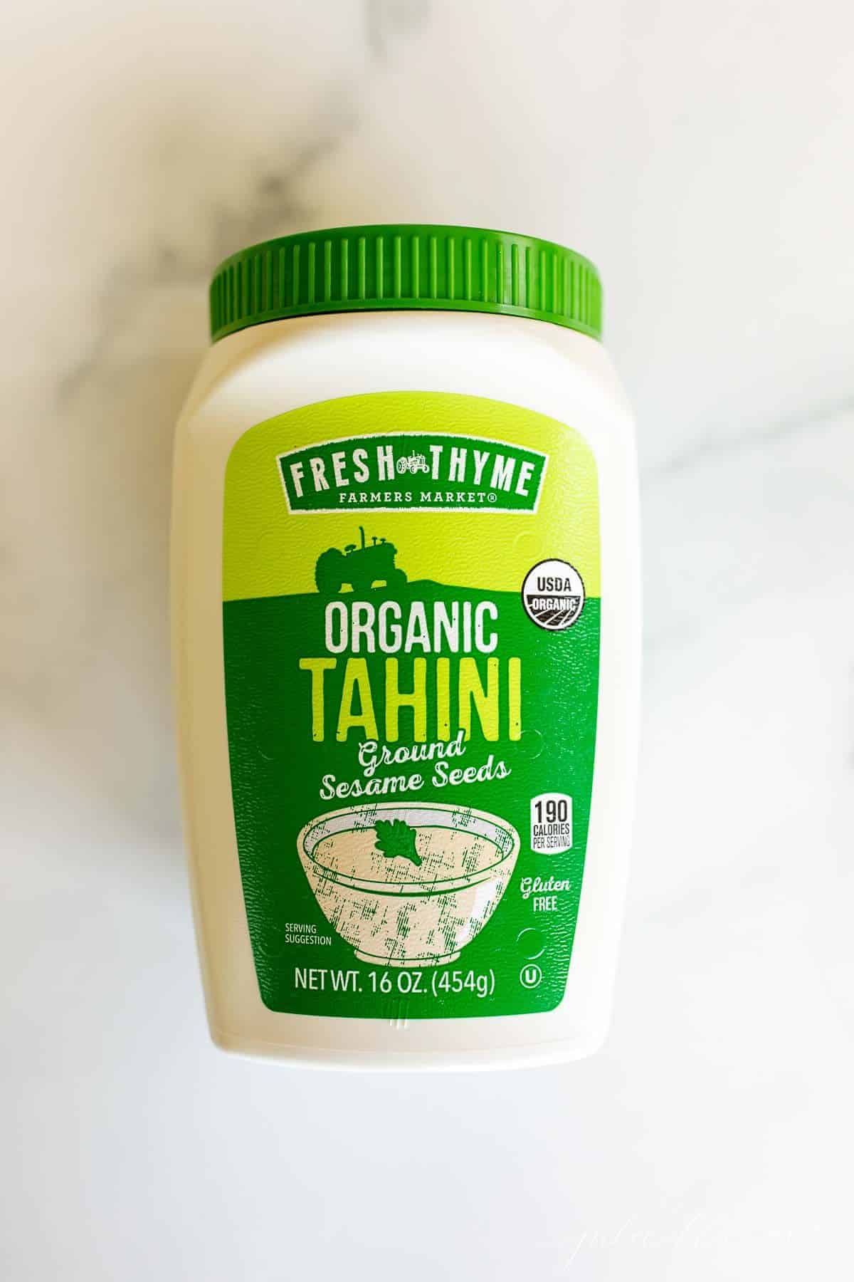 A marble surface with a bottle full of organic tahini.