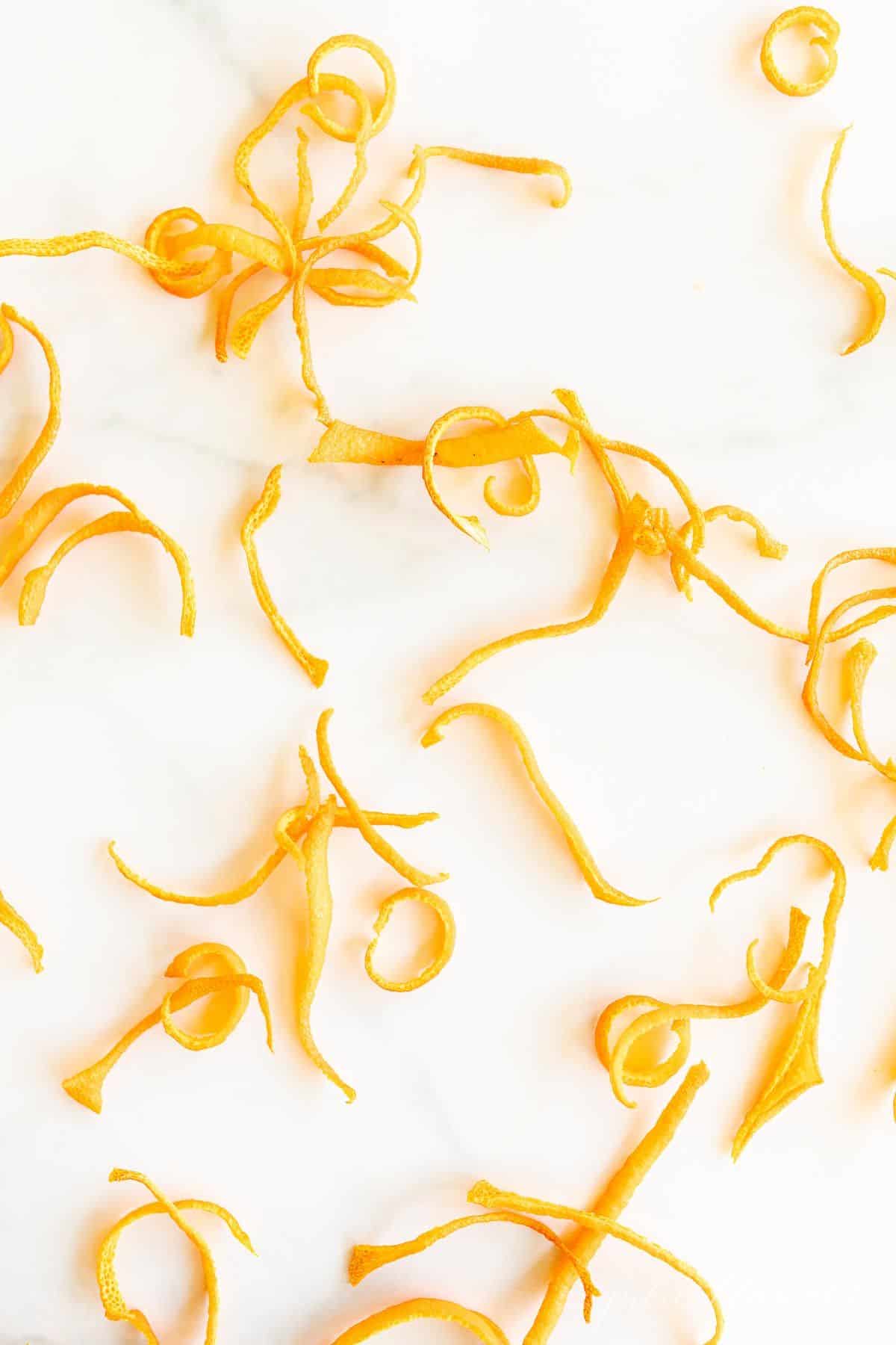 A marble surface with curls of dried orange zest to make dried orange powder.