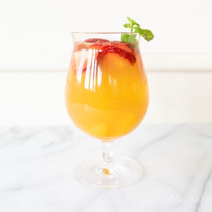peach sangria in a glass with strawberries and garnished with mint