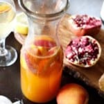 prosecco sangria in carafe by peach and pomegranates