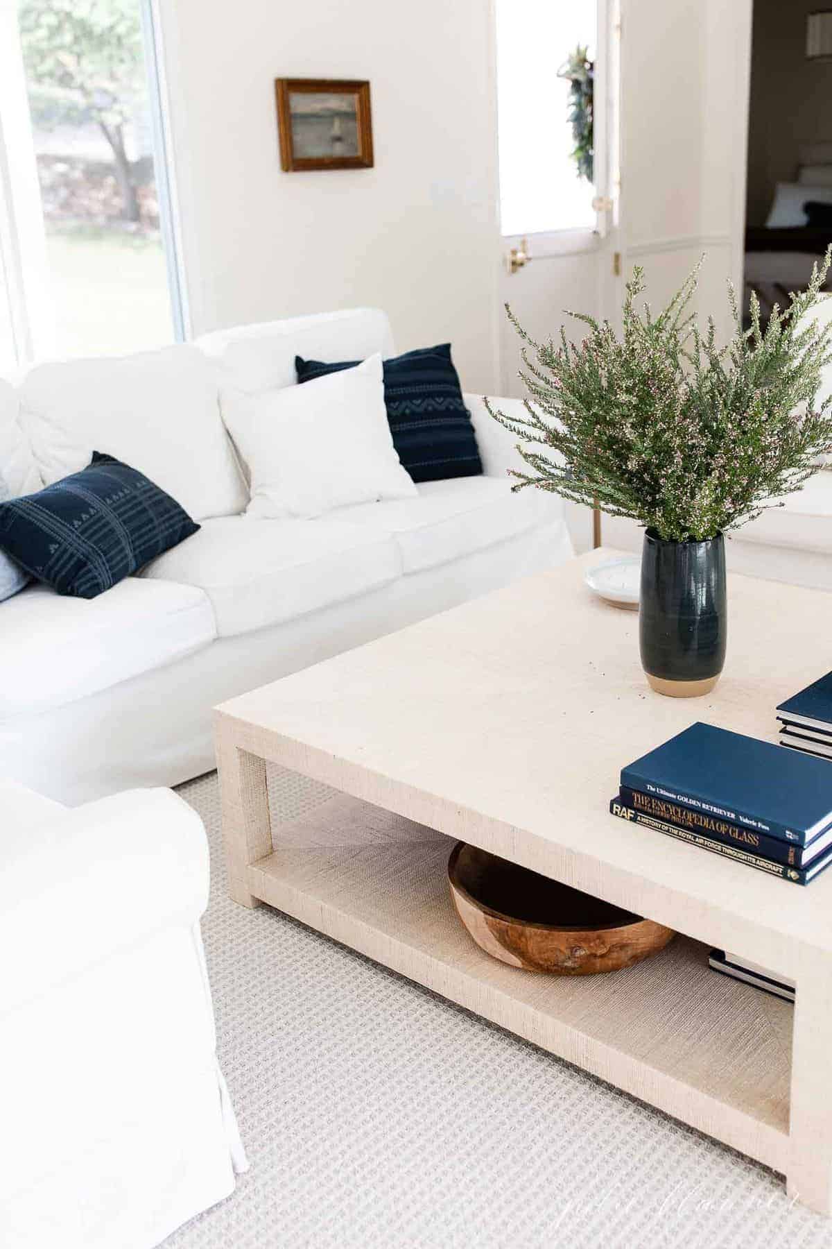 A white living room with navy pillows and a navy vase full of fall wildflowers.