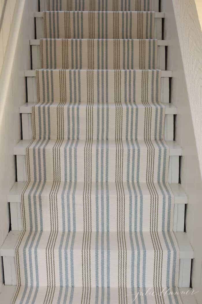 A striped stair runner on basement stairs, made from an indoor outdoor rug.