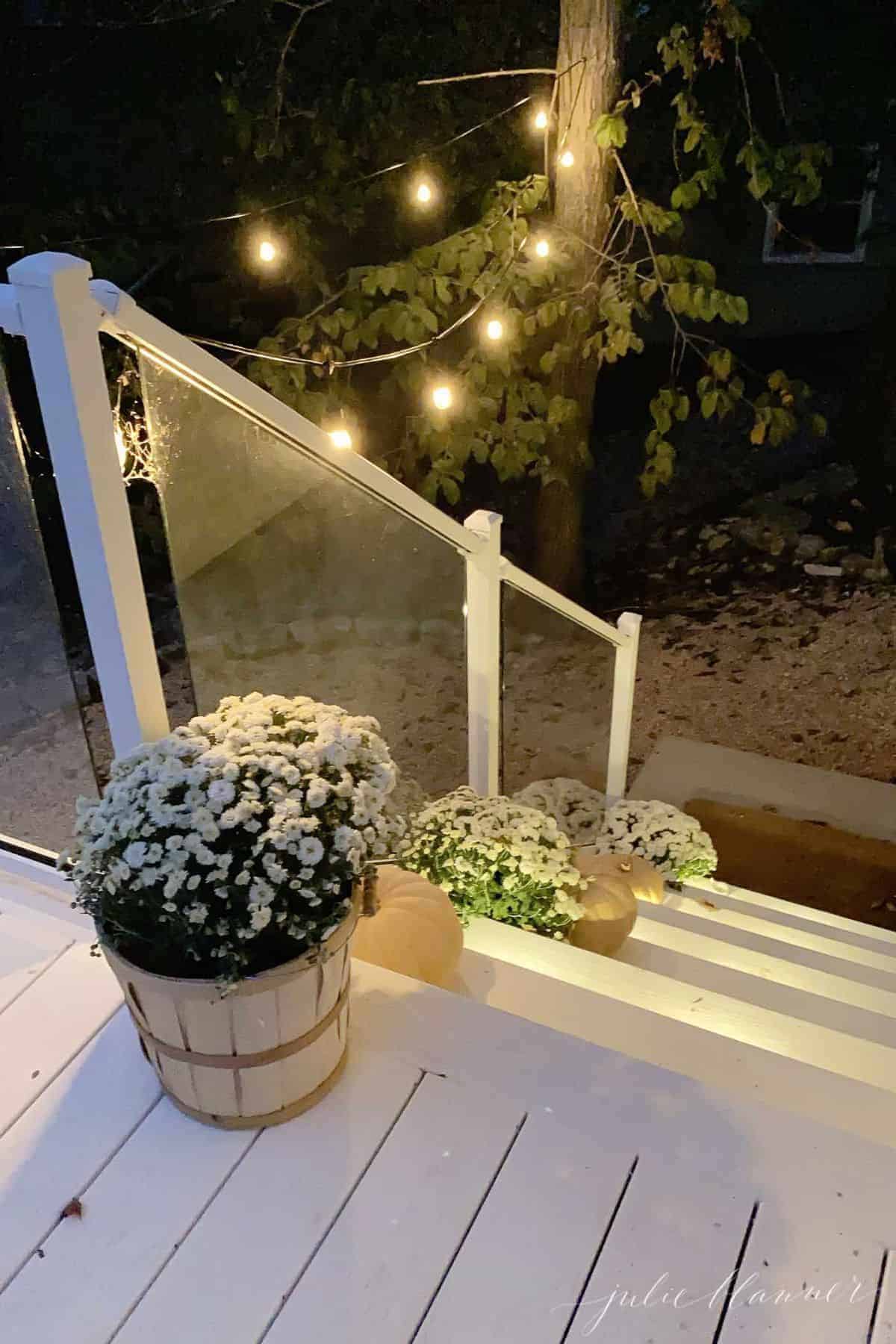 White porch steps with Halloween porch decorations of mums and pumpkins and spider webs