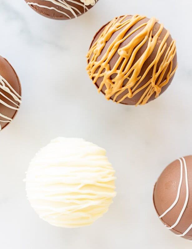 A marble surface with a variety of hot chocolate bombs.