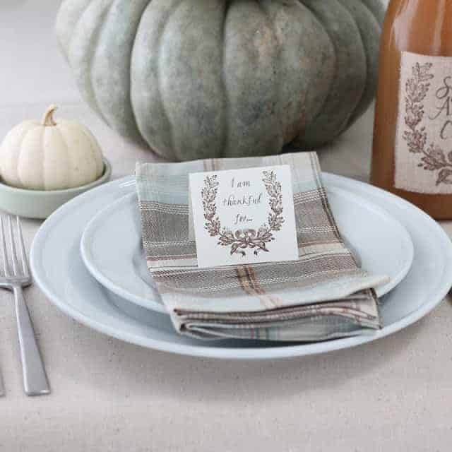 A table set for Thanksgiving with a small card that states "thankful for" on top of napkin.