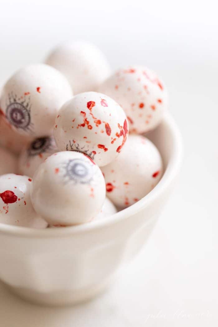 A white bowl full of bloody eyeball gumballs for Halloween.