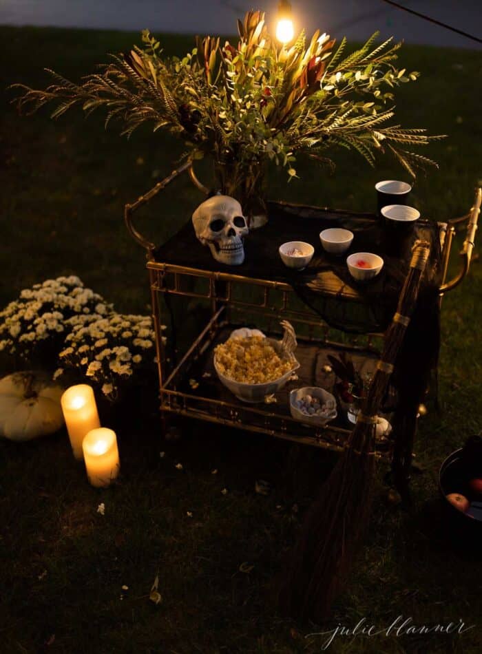 An outdoor movie set up in a yard for halloween, with a skeleton, candles and decorations.