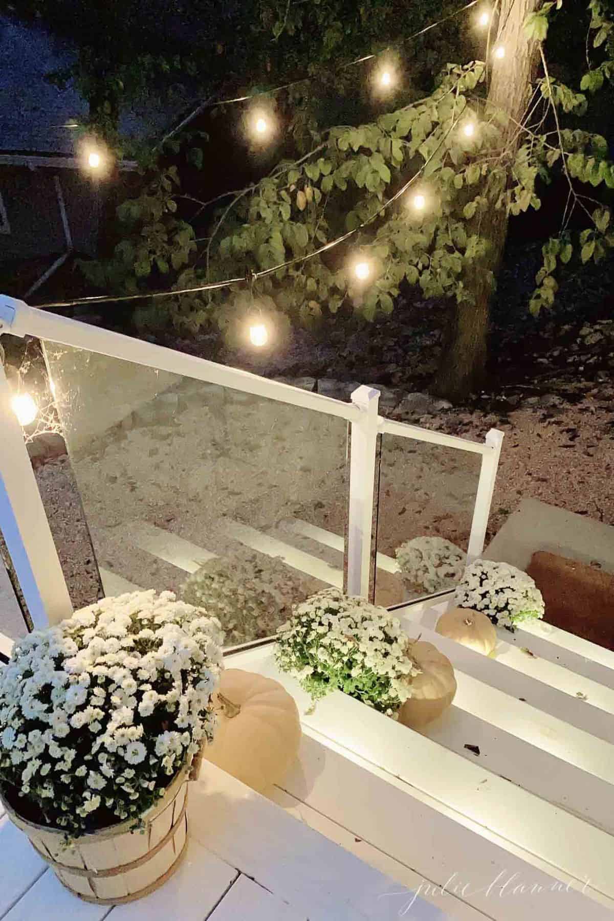 White porch steps with Halloween porch decorations of mums and pumpkins and spider webs