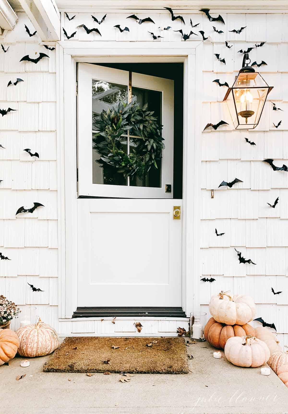 open dutch door surrounded by black bats and pumpkins