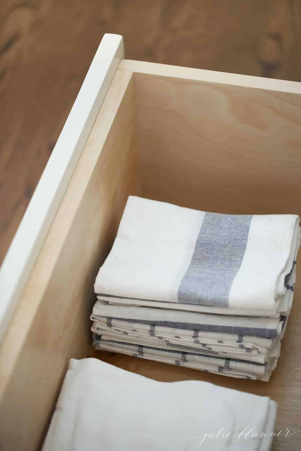 Looking inside a kitchen drawer filled with stacks of striped kitchen towels.