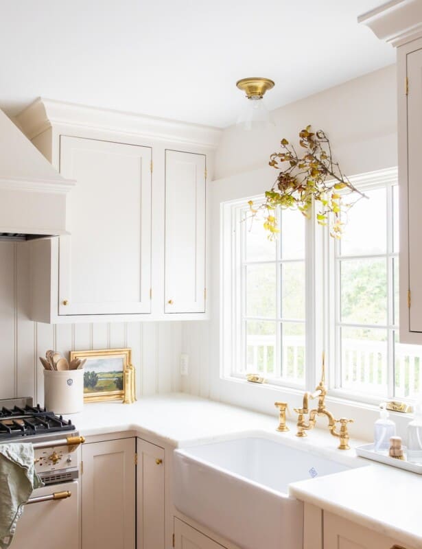 A white kitchen with a fall branch hanging over the kitchen sink window.