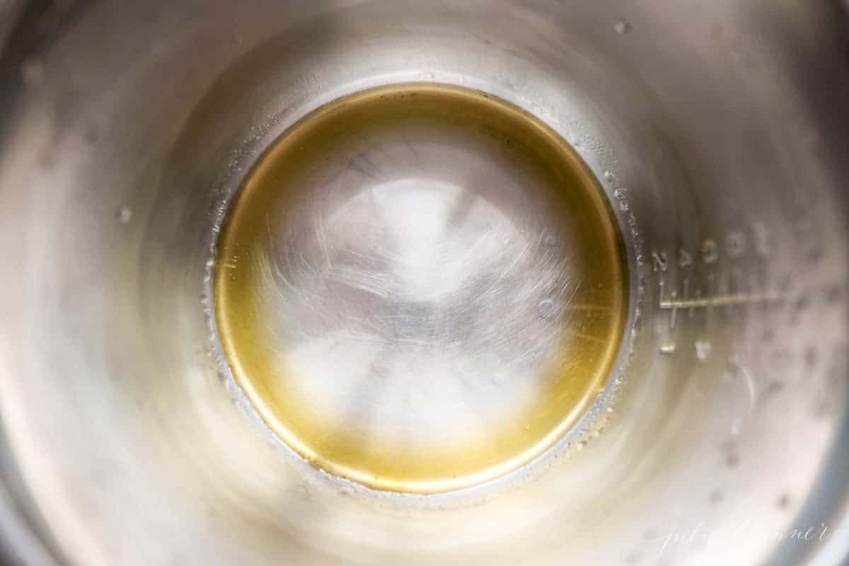 Looking into a silver stovetop pot full of warmed olive oil.