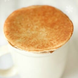 A stroopwafel on top of a white coffee mug.