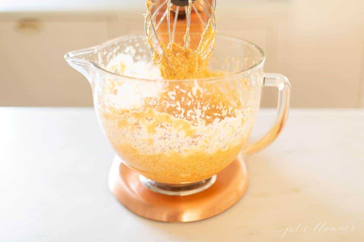 A copper kitchen aid mixer with a glass bowl mixing sweet potatoes for a side dish.