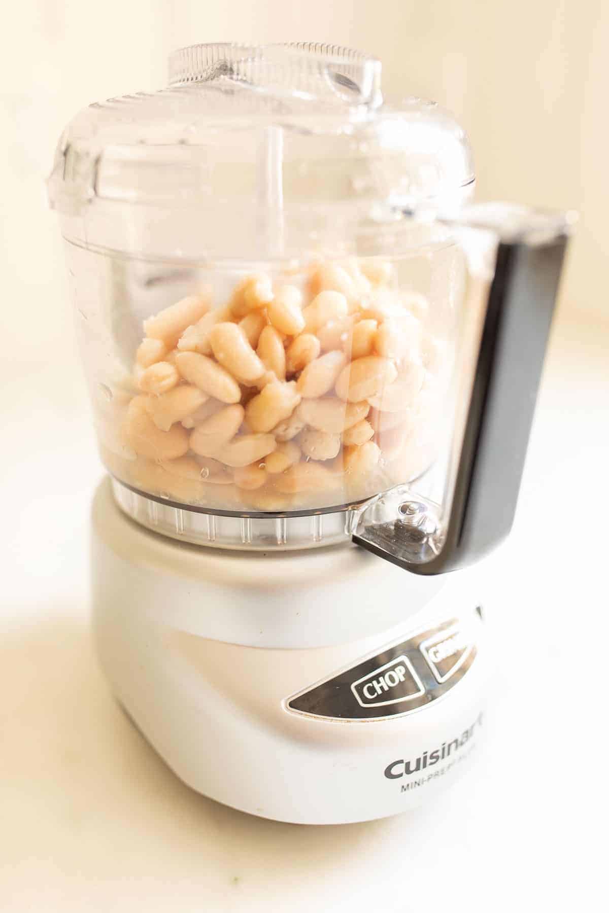 A food processor filled with cannellini beans for white bean dip.