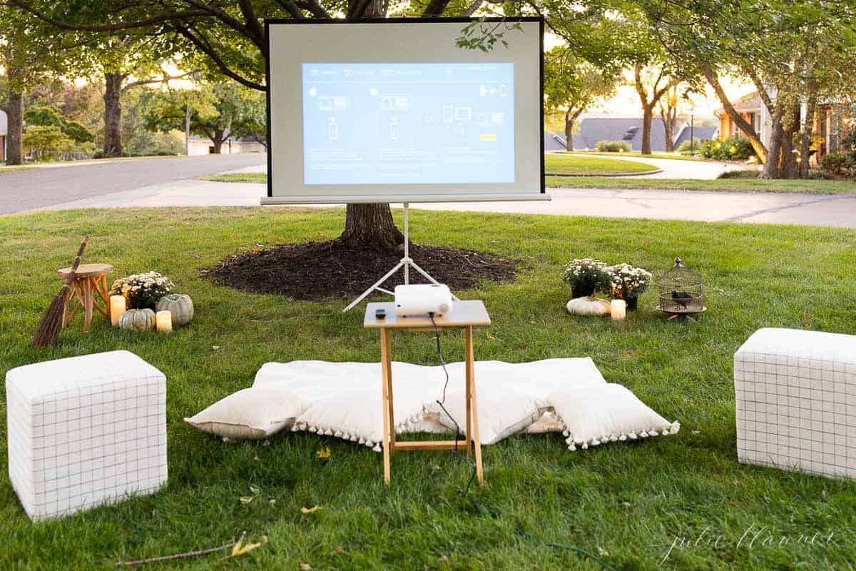 An outdoor movie set up in a yard for halloween, with candles and decorations.