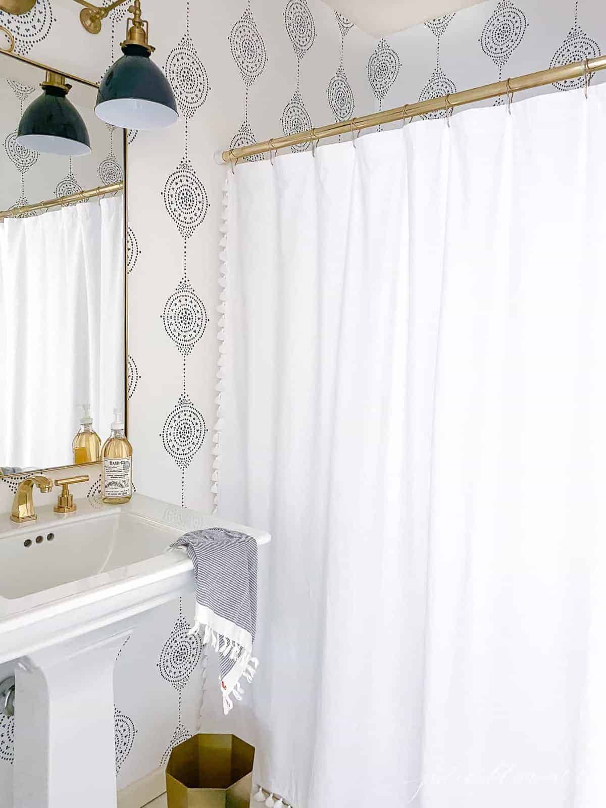 A small bathroom with blue and white wallpaper and a pedestal sink