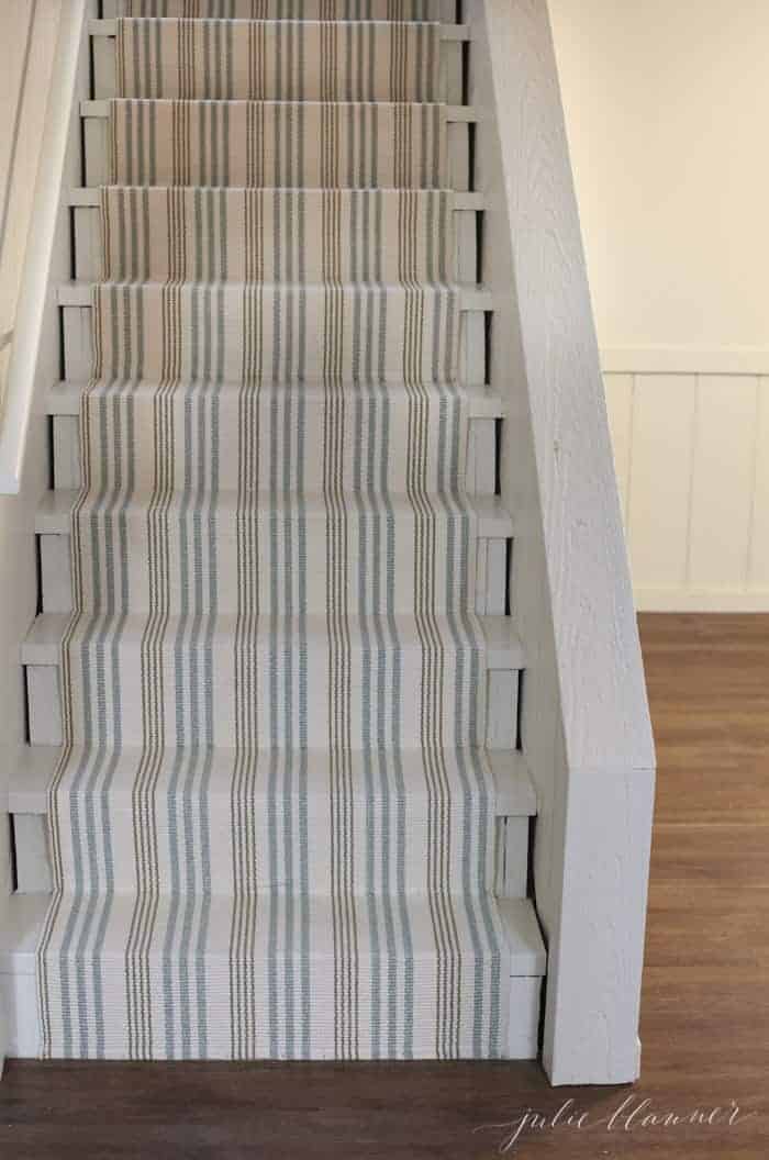 A striped stair runner on basement stairs, made from an indoor outdoor rug.