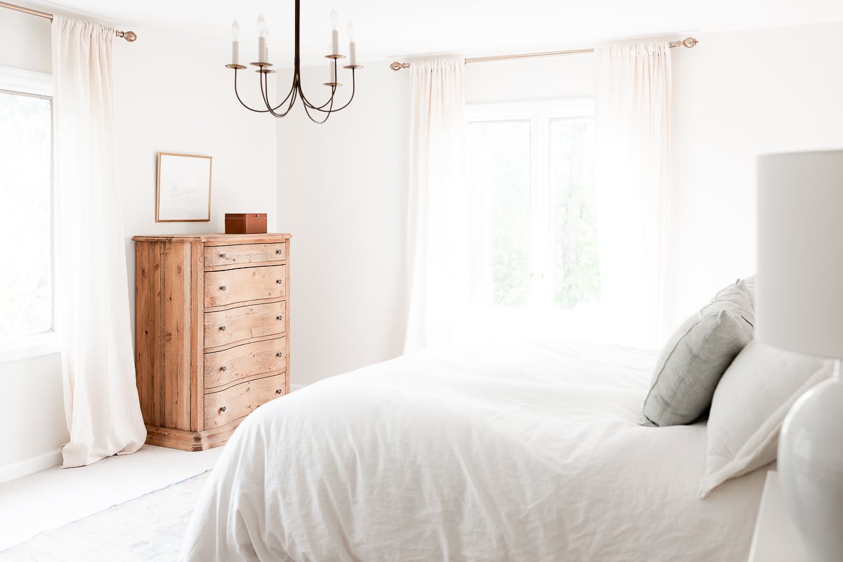 A bedroom with a minimalist aesthetic in shades of cream with touches of blue.