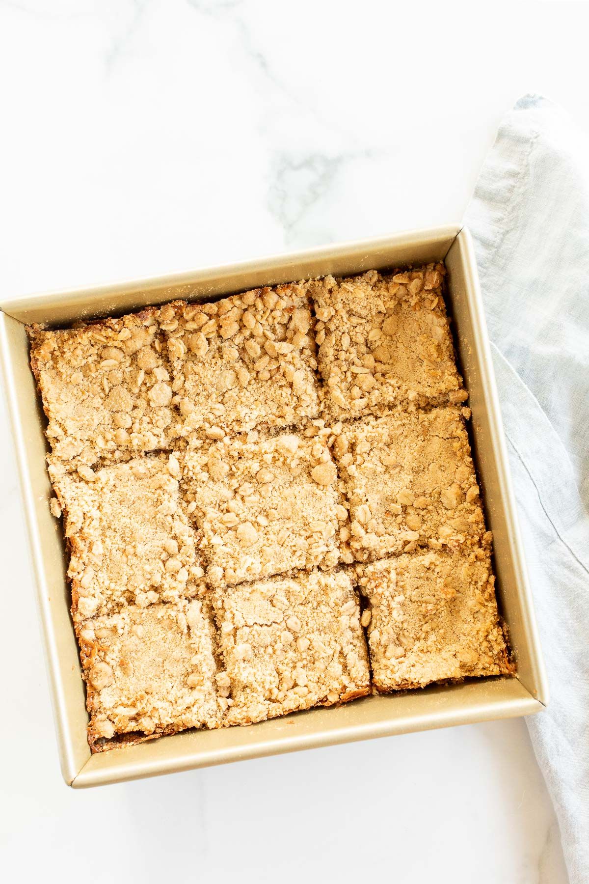 Caramel oatmeal chocolate chip bars baked in a gold baking pan, sliced for serving.
