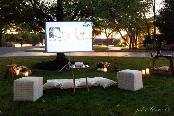 An outdoor movie set up in a yard for halloween, with a skeleton, candles and decorations.