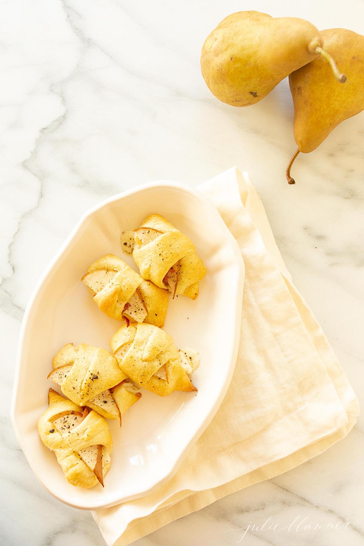 Pear crescent roll appetizers on a white platter. 