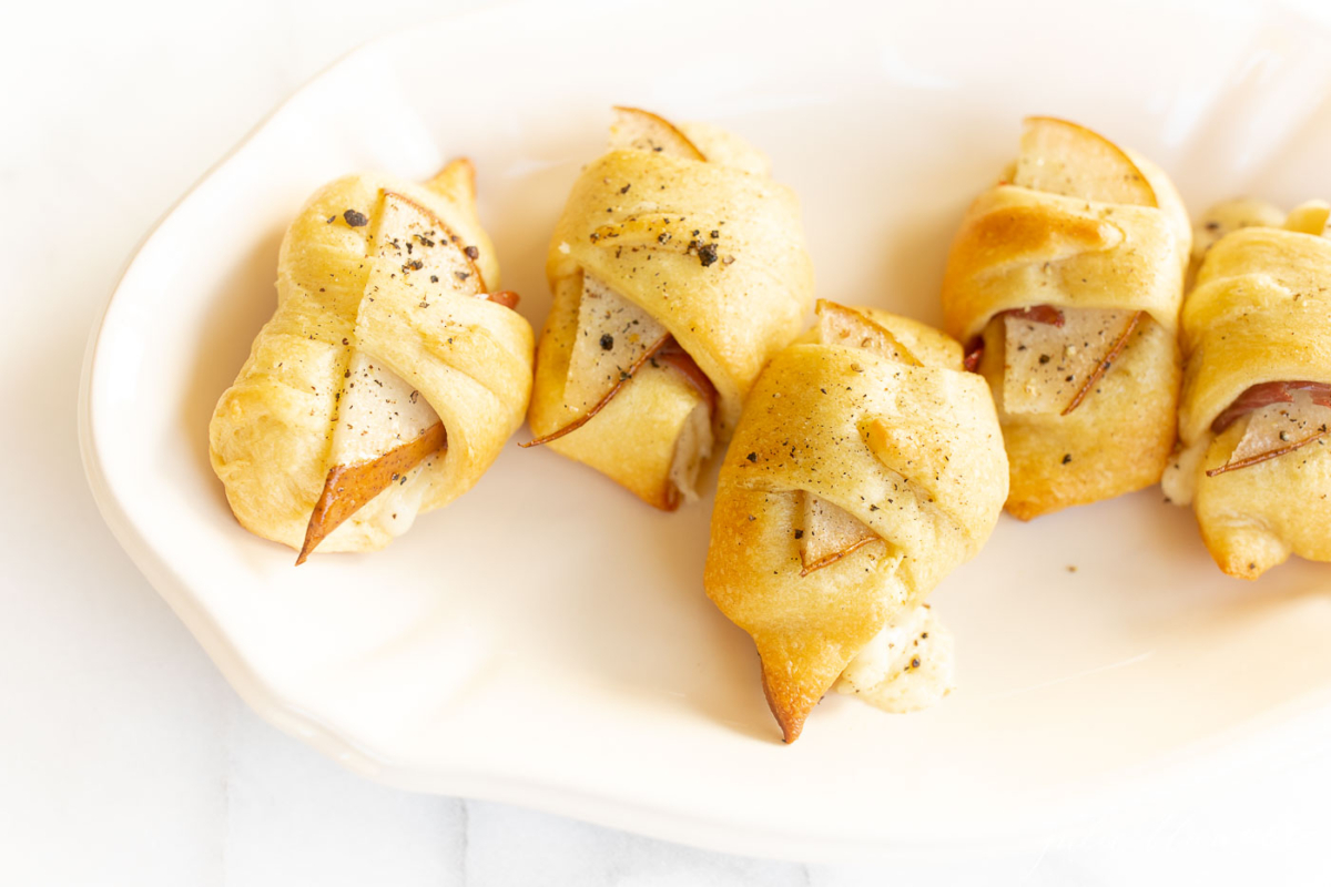 Pear crescent roll appetizers on a white platter. 