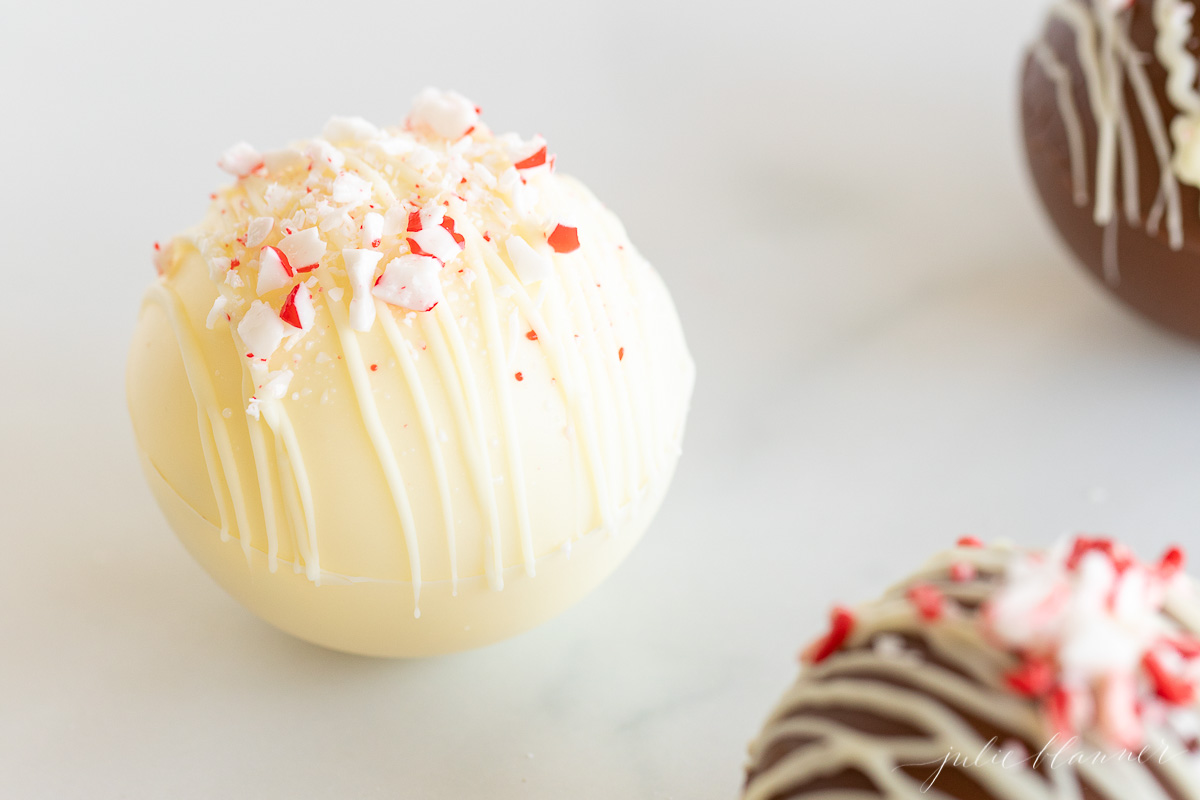 Three white peppermint balls on a white surface.