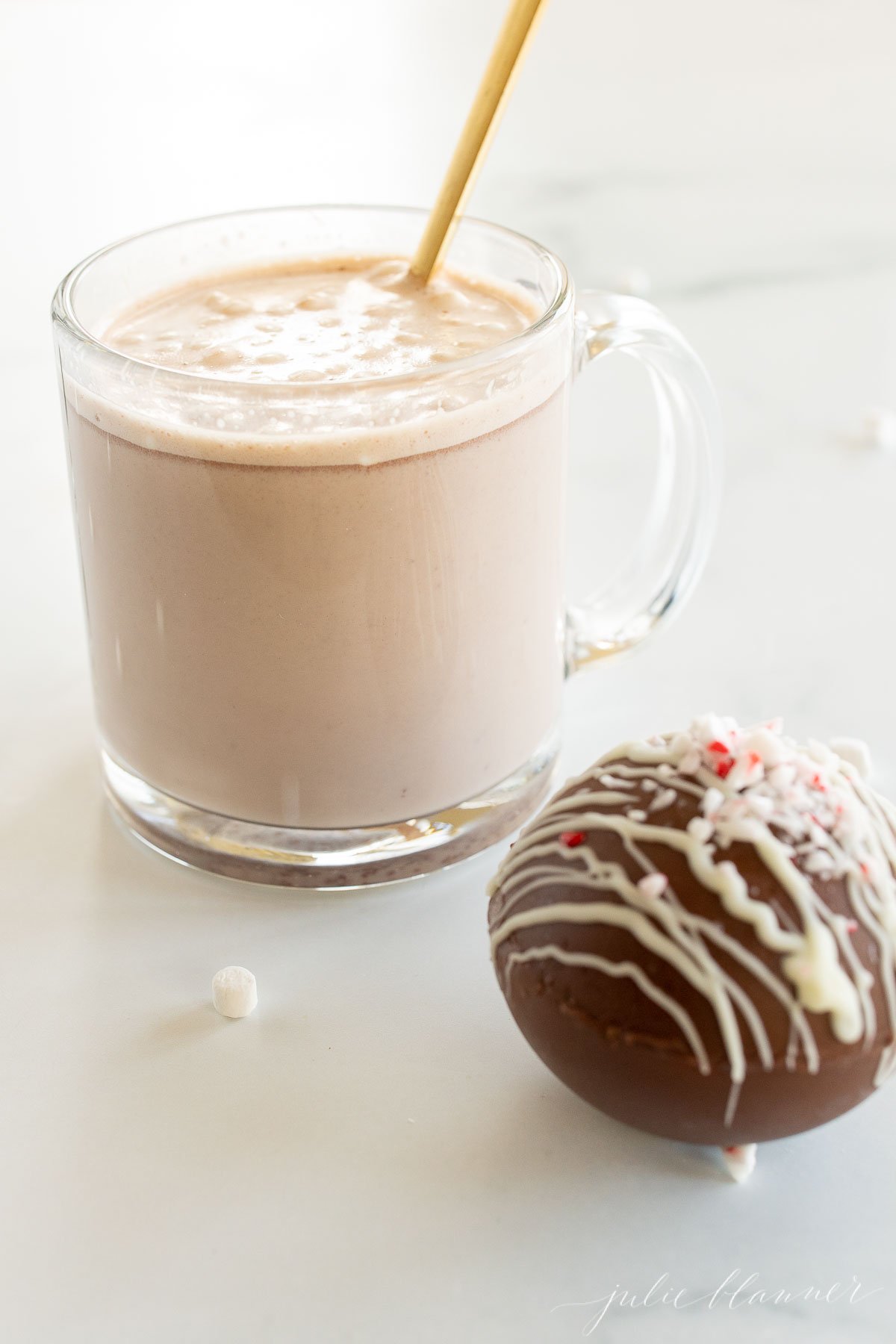 A cup of peppermint hot chocolate with a donut next to it.