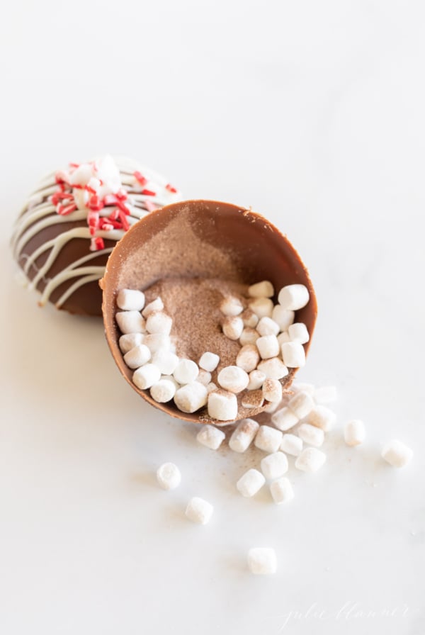 A peppermint hot chocolate bomb with marshmallows and sprinkles.