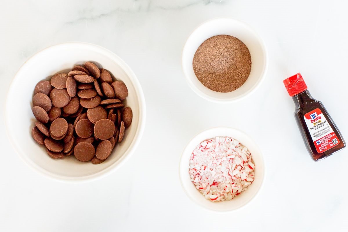Ingredients for peppermint hot chocolate bombs on a white marble countertop