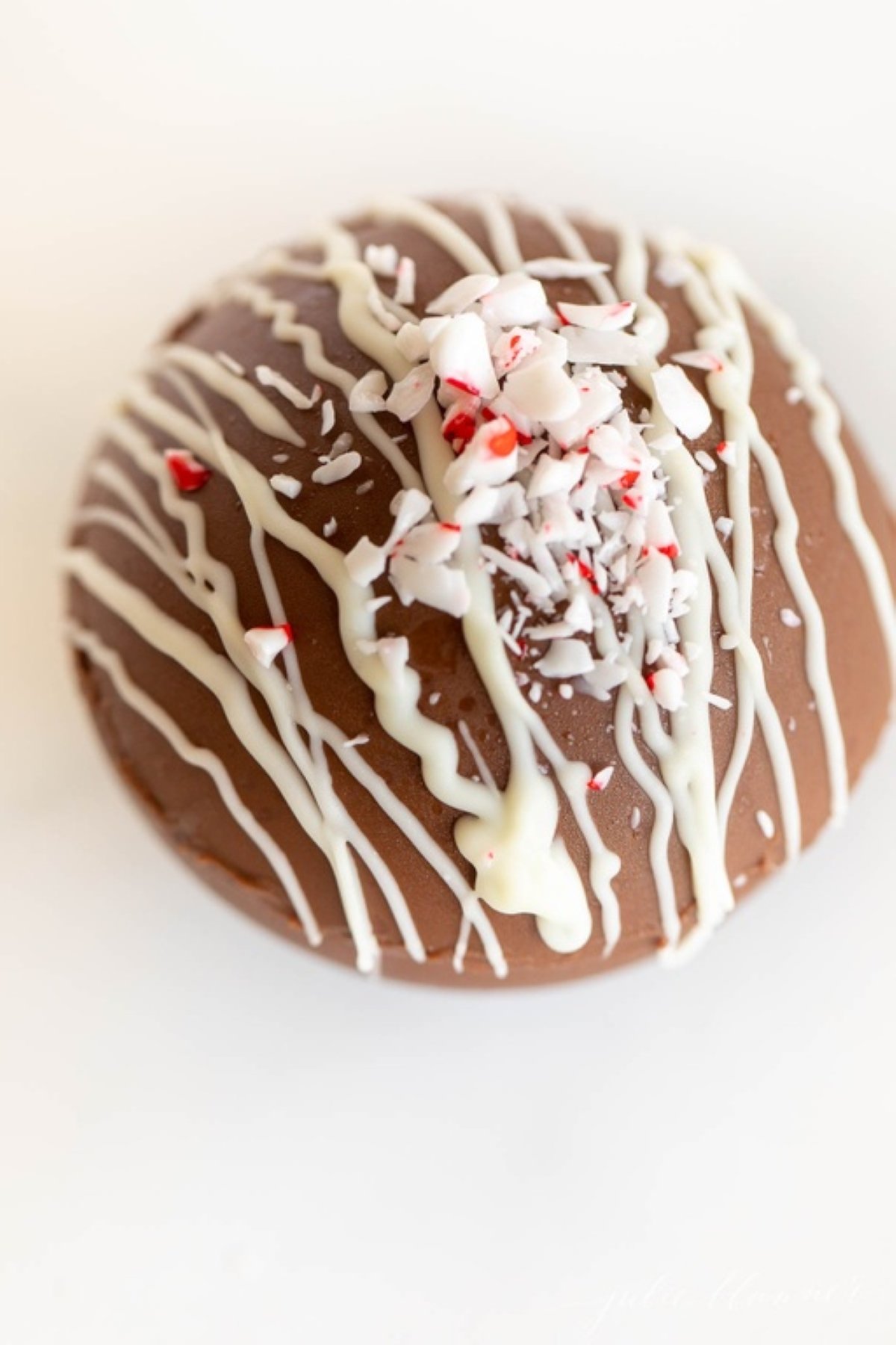 A peppermint hot chocolate bomb on a white marble surface