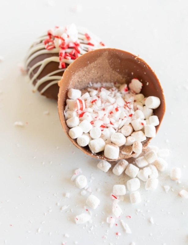 A peppermint hot chocolate bomb, broken open with contents spilling out across a white countertop