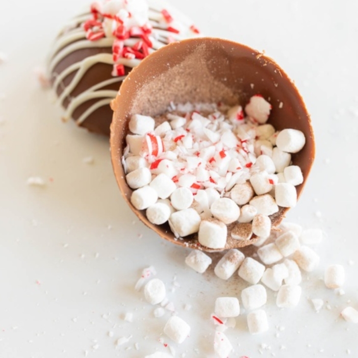 A peppermint hot chocolate bomb, broken open with contents spilling out across a white countertop