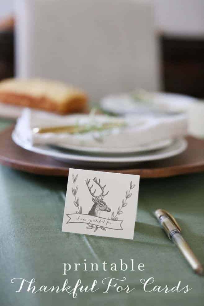 A table set for Thanksgiving with a small free printable card with a deer antler illustration that states "things to be grateful for".