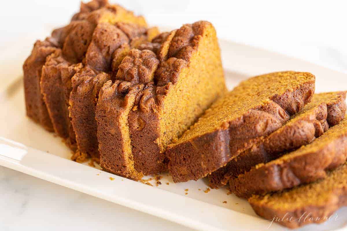 A white platter with a pumpkin bread recipe cut into slices