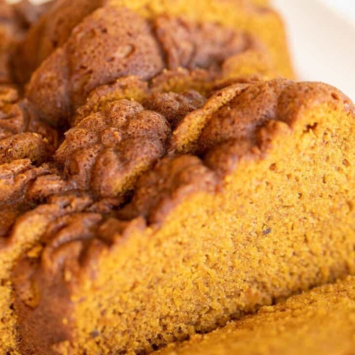 A white platter with a pumpkin bread recipe cut into slices