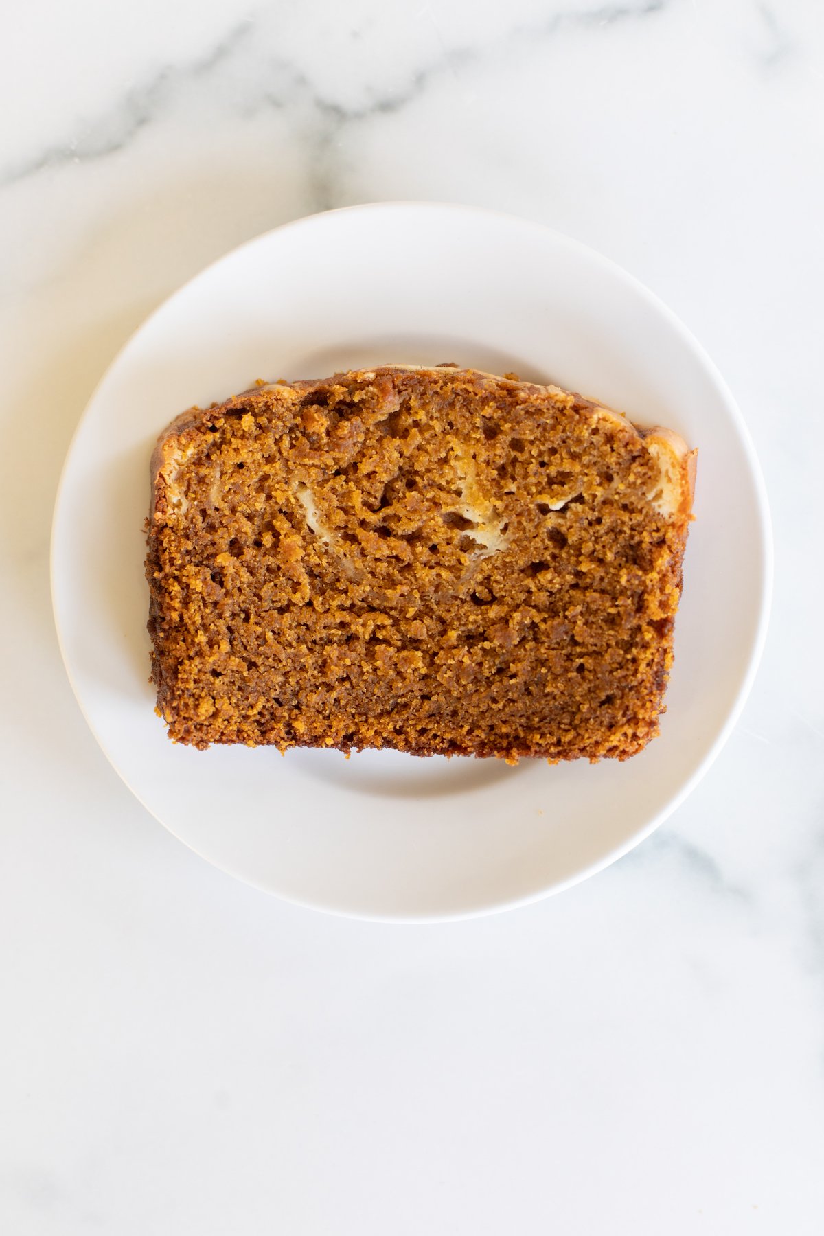 A slice of pumpkin cheesecake bread on a white plate.