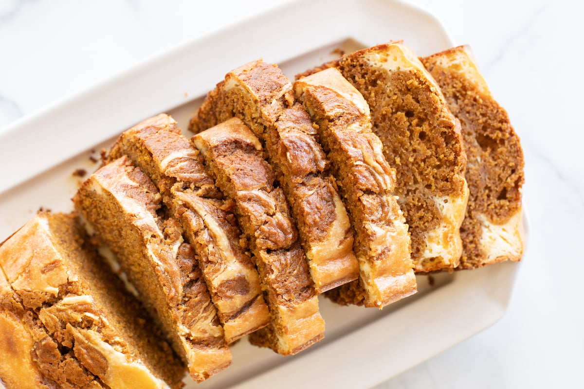 A loaf of pumpkin cheesecake bread on a white platter.