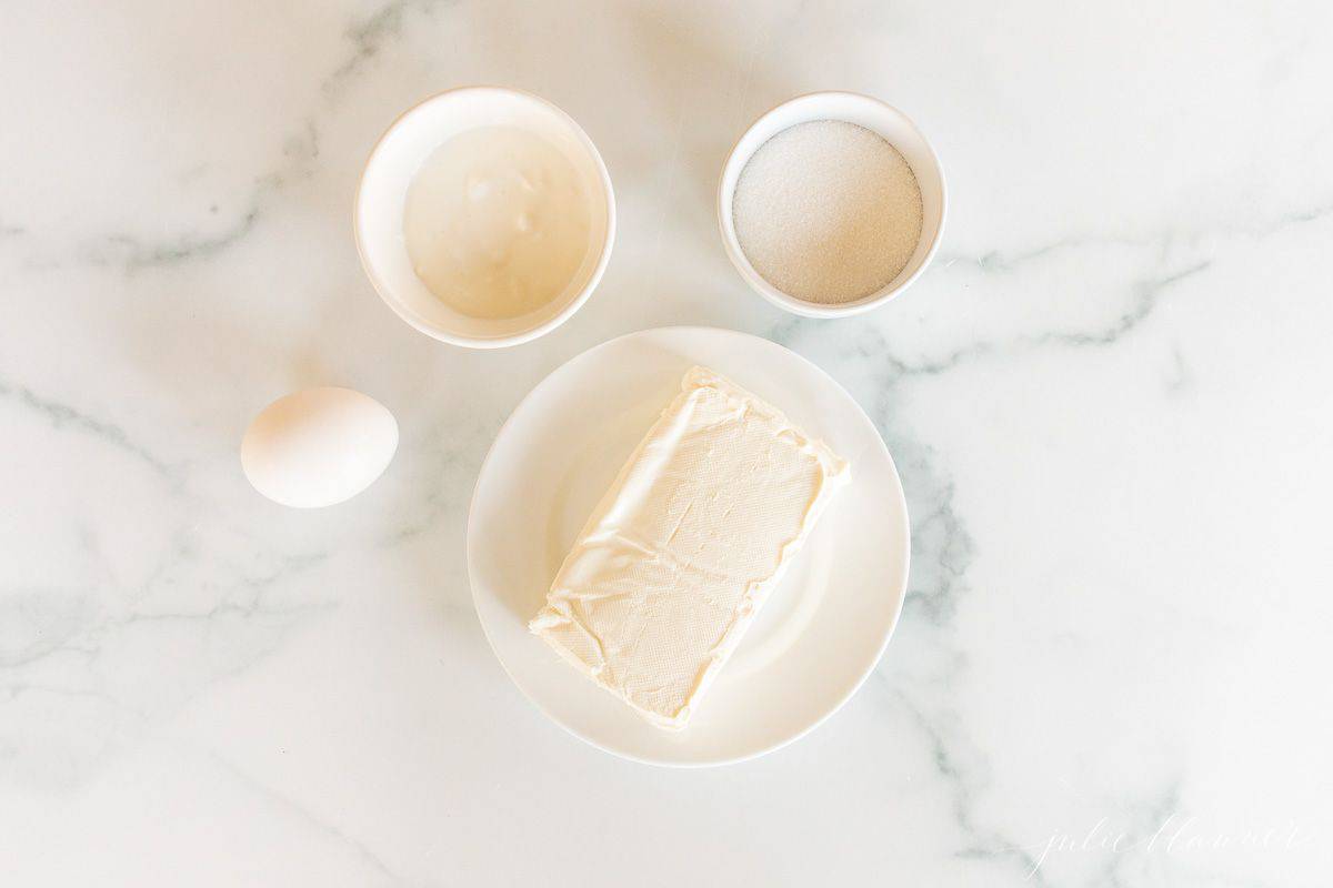 A marble surface with ingredients for pumpkin cheesecake bread.