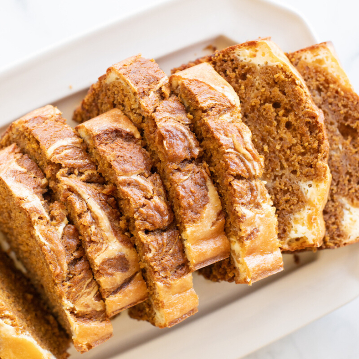 A loaf of pumpkin cheesecake bread on a white platter.