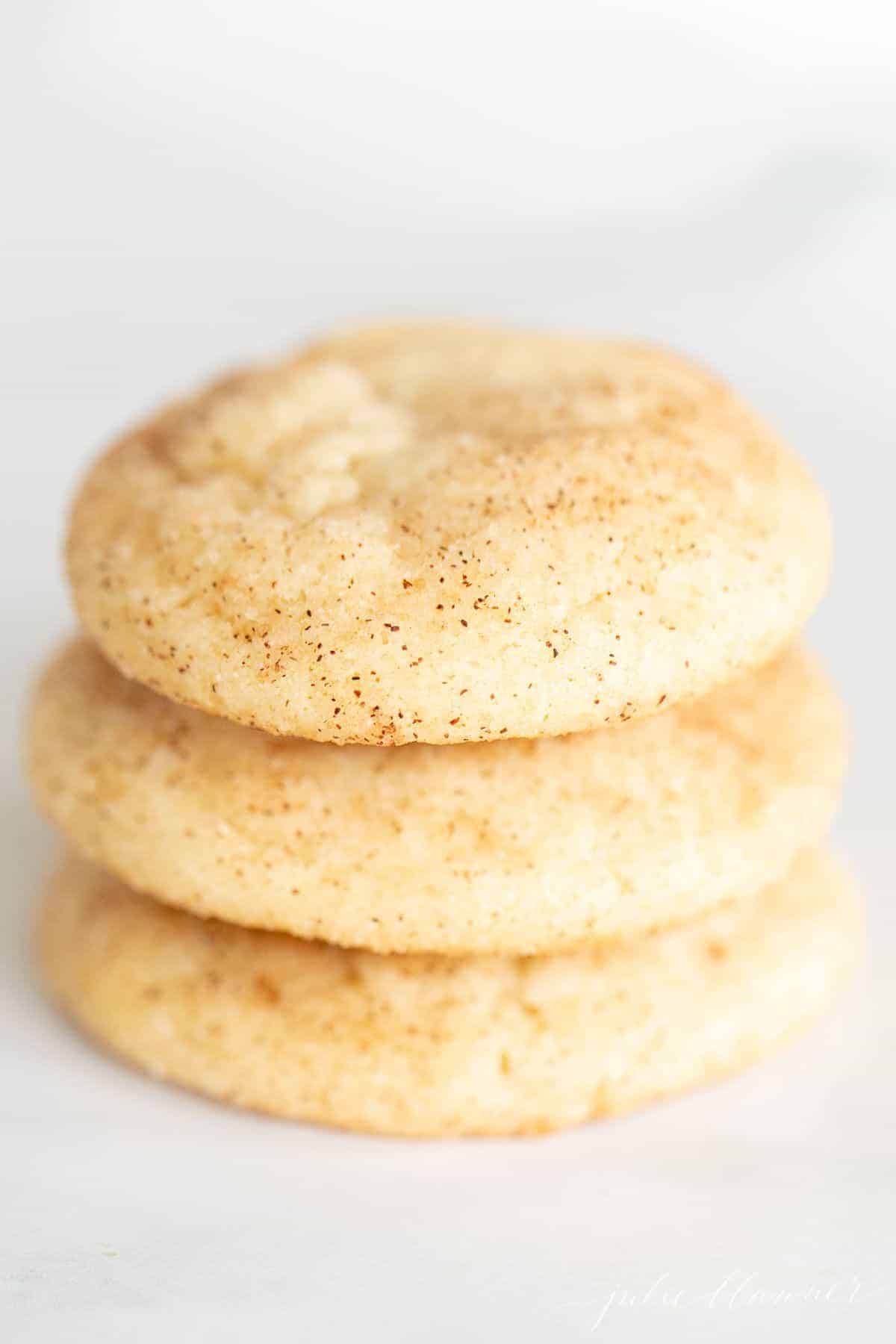 A stack of three snickerdoodle cookies without cream of tartar on a marble surface.