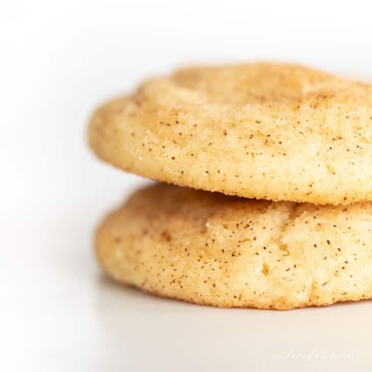 Two Snickerdoodle cookies without cream of tartar stacked on a white surface.