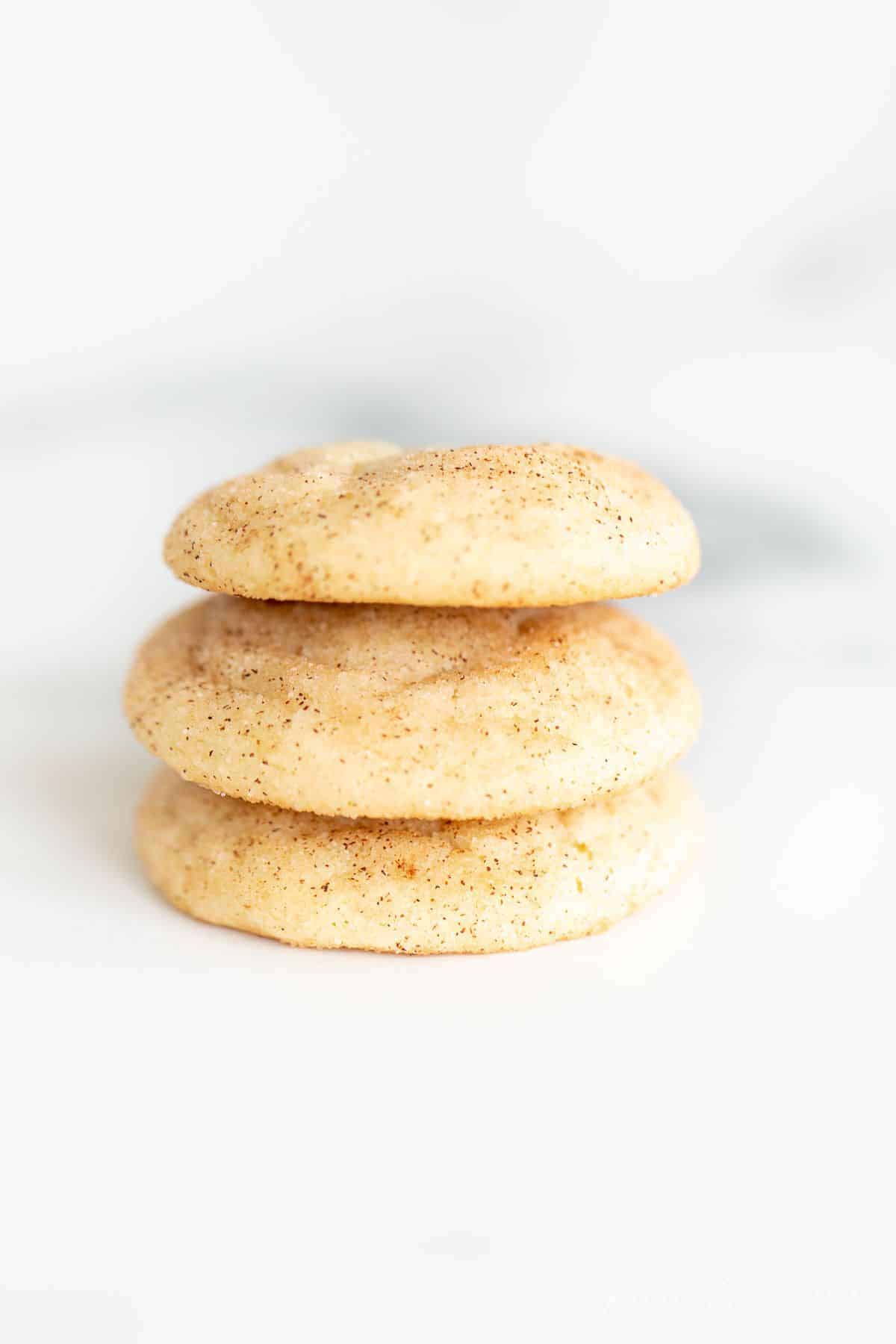 A stack of three snickerdoodle cookies without cream of tartar on a marble surface.