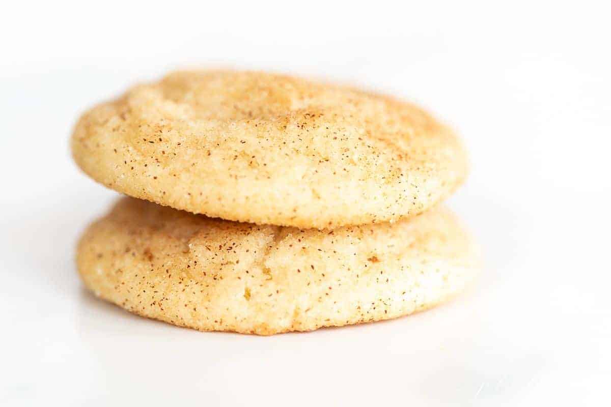 Two Snickerdoodle cookies without cream of tartar stacked on a white surface.