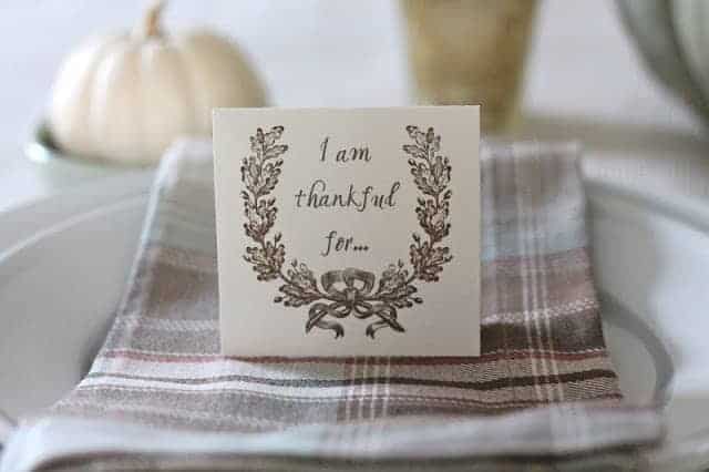 A table set for Thanksgiving with a small card that states "thankful for" on top of napkin.
