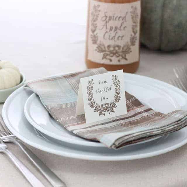 A table set for Thanksgiving with a small card that states "thankful for" on top of napkin.